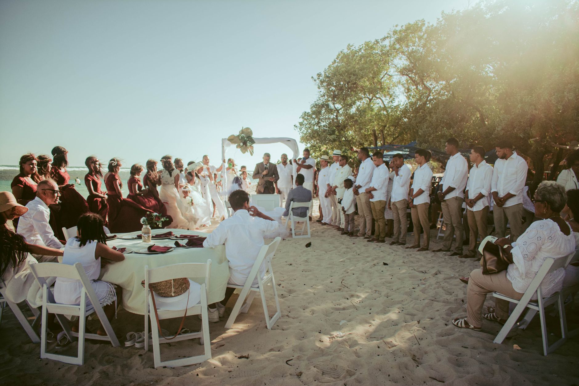 Guests at a beach wedding in light linen suits and flowing pastel dresses