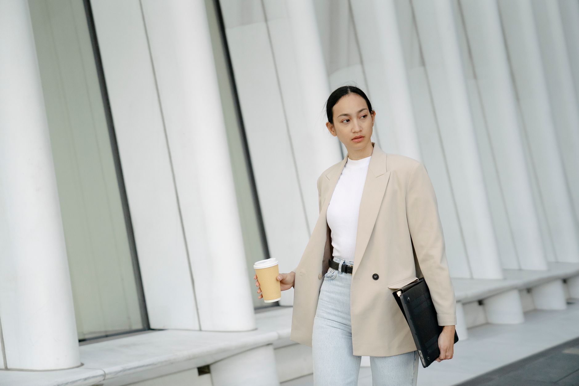 Woman wearing dark straight-leg jeans with a blouse and longline blazer at work