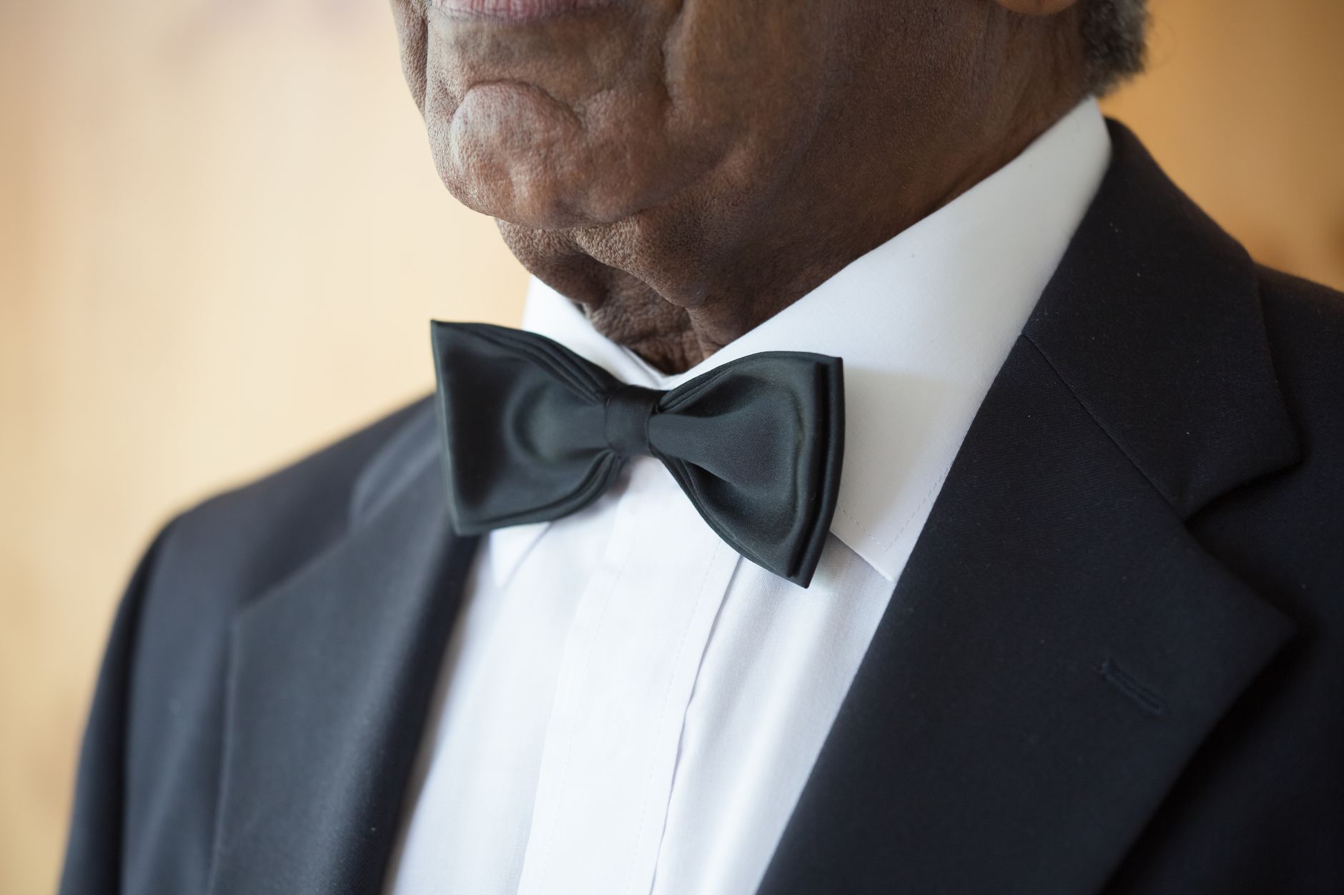 Man in black tuxedo with white waistcoat and black bow tie