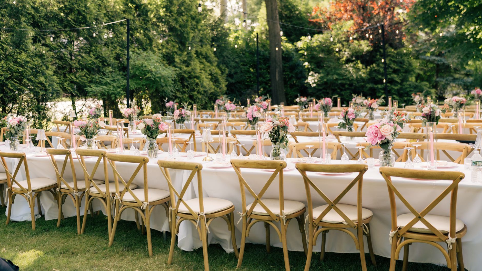 Outdoor garden wedding reception setup with string lights and set tables