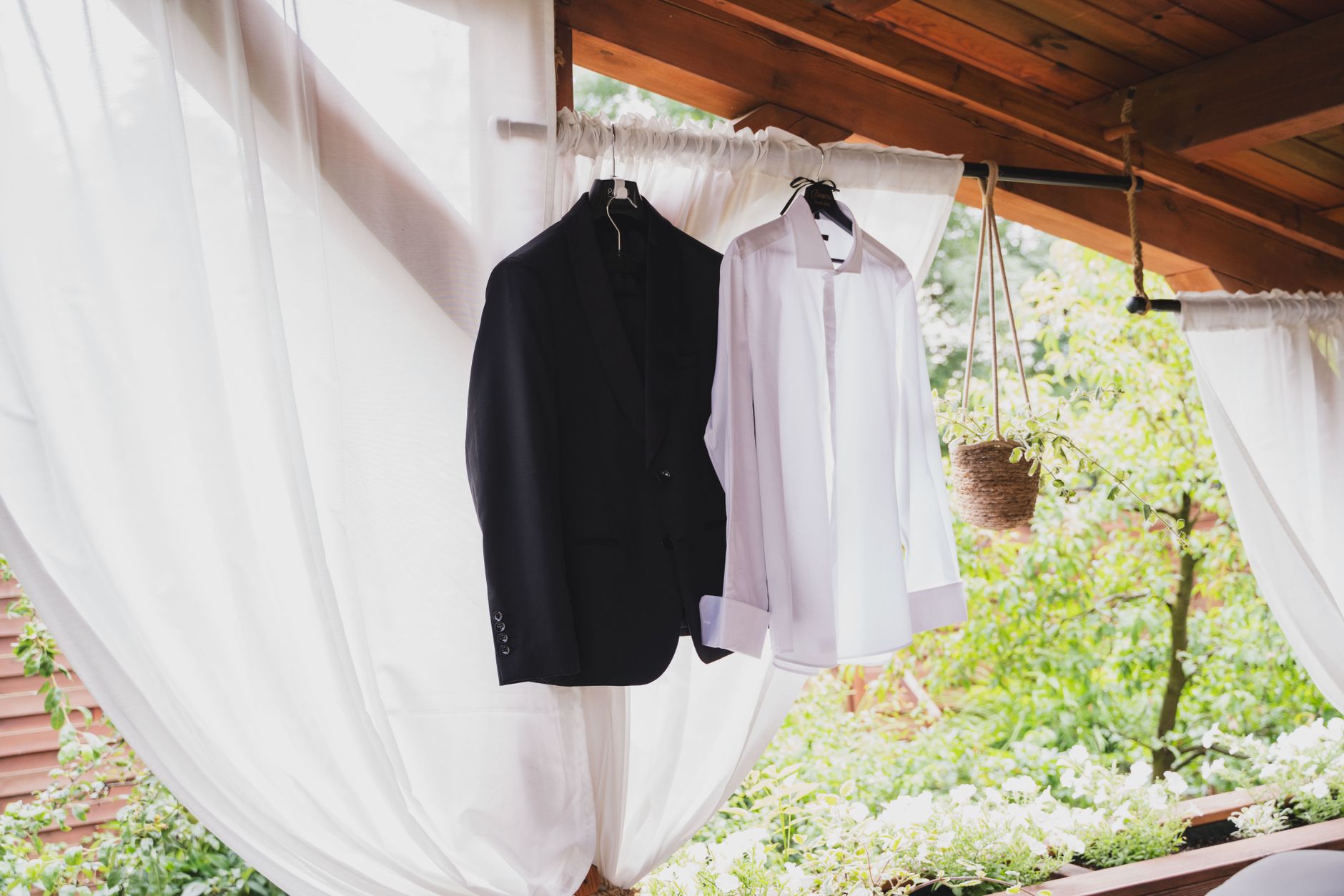 Black tuxedo and navy suit hanging side by side on a rail