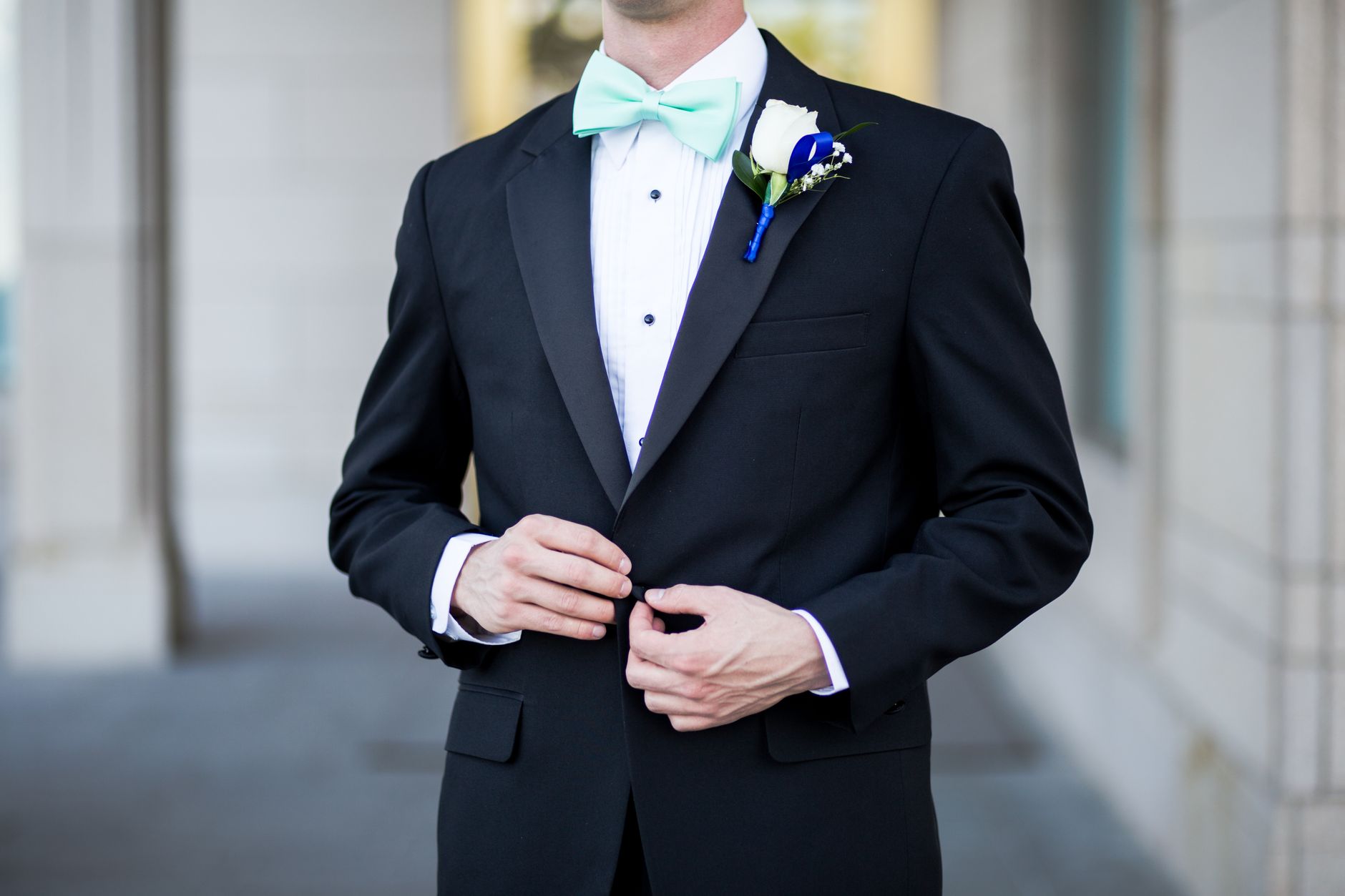 Groom in a black tuxedo wearing silk formal suspenders and a bow tie