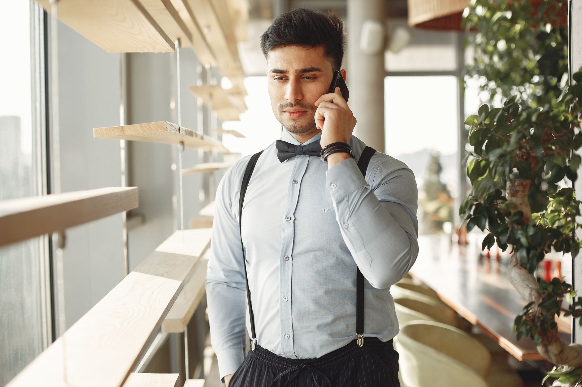 White dress shirt with navy suspenders and grey pleated trousers in an office