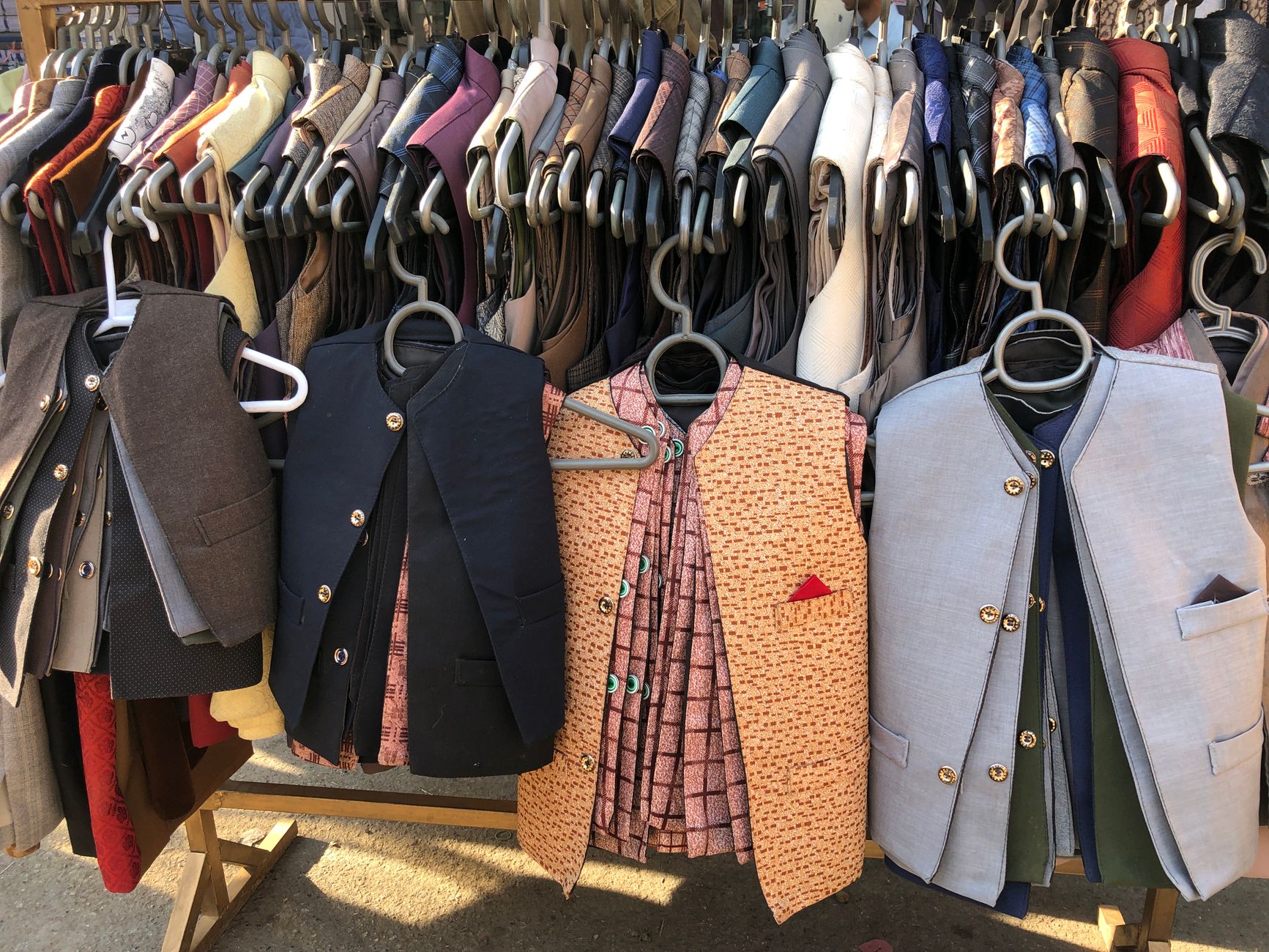 Thrift store rack of brown waistcoats, tweed jackets and leather belts