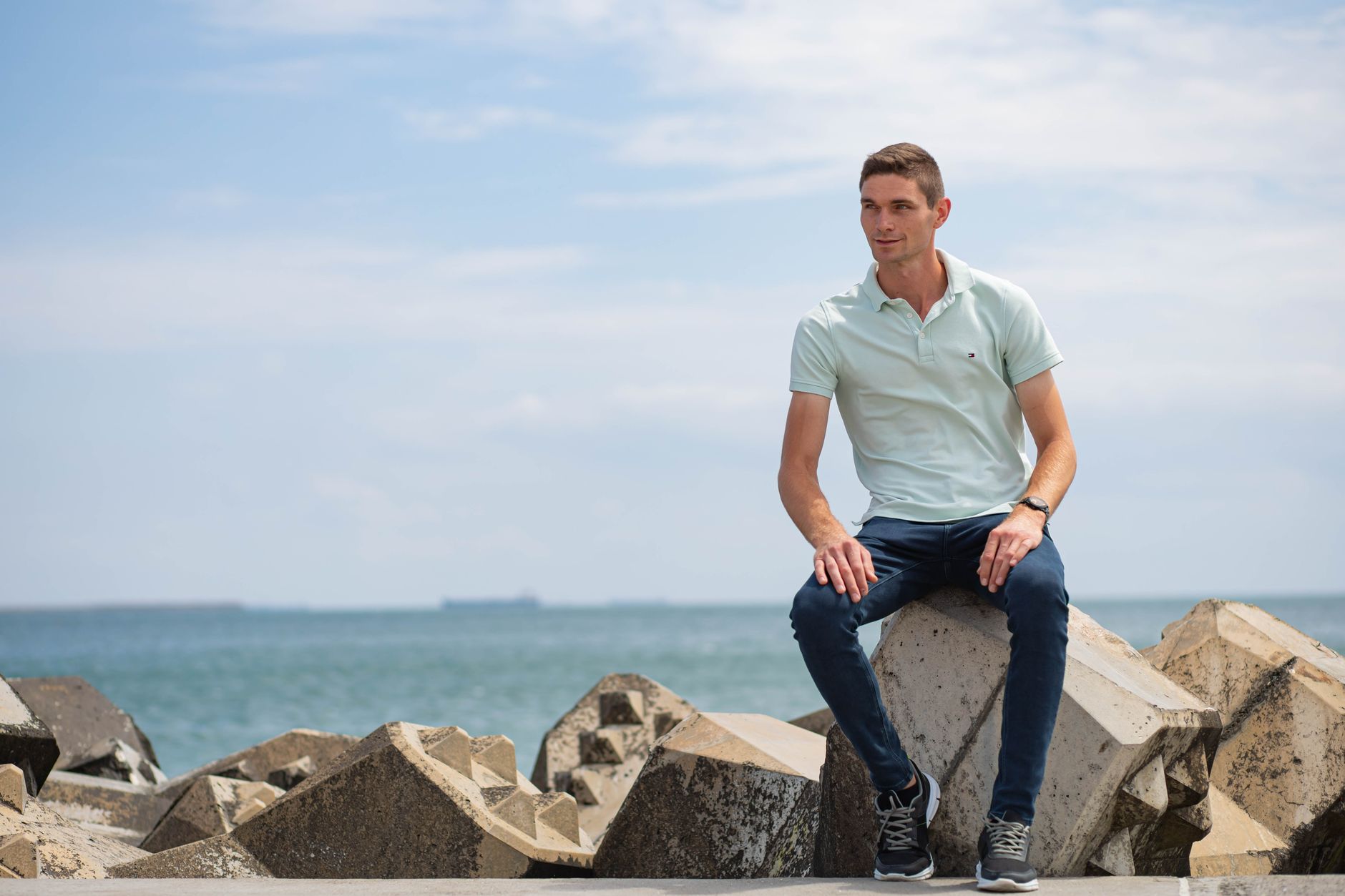Man in a navy knit polo with chinos and white leather sneakers