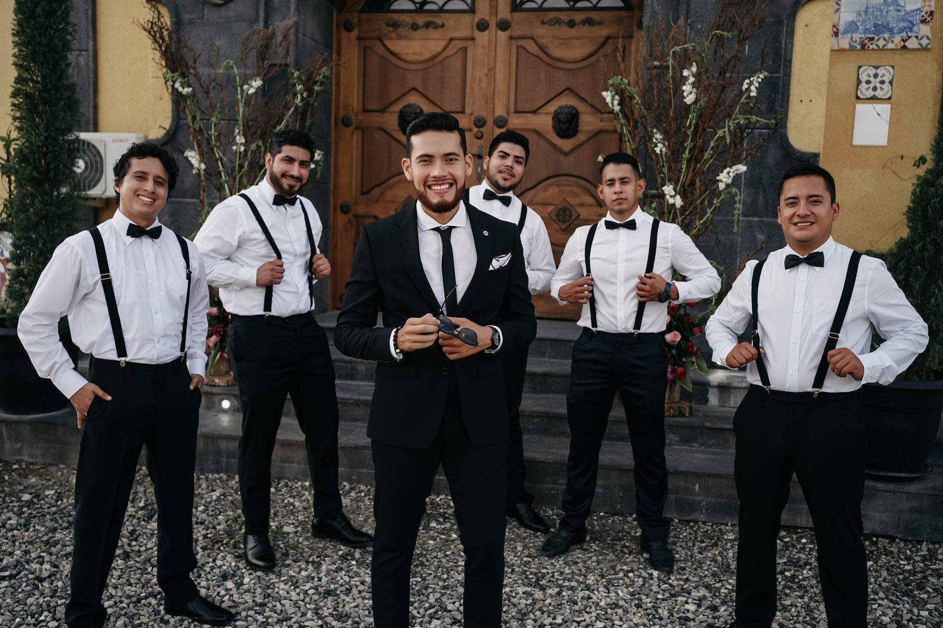 Groomsmen coordinated in matching suspenders and bow ties before the ceremony