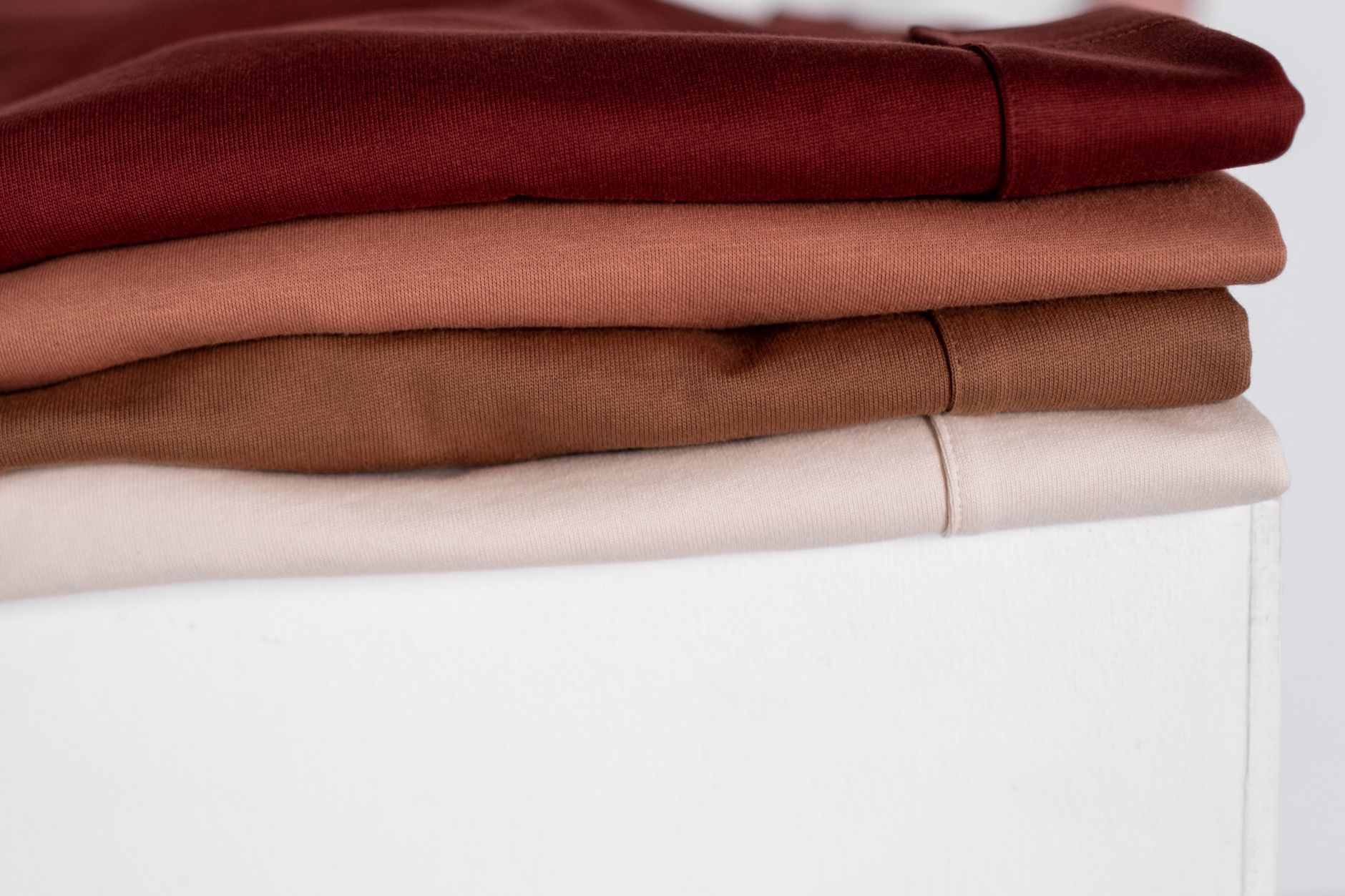 Folded chinos in navy, charcoal, stone and khaki stacked on a shelf