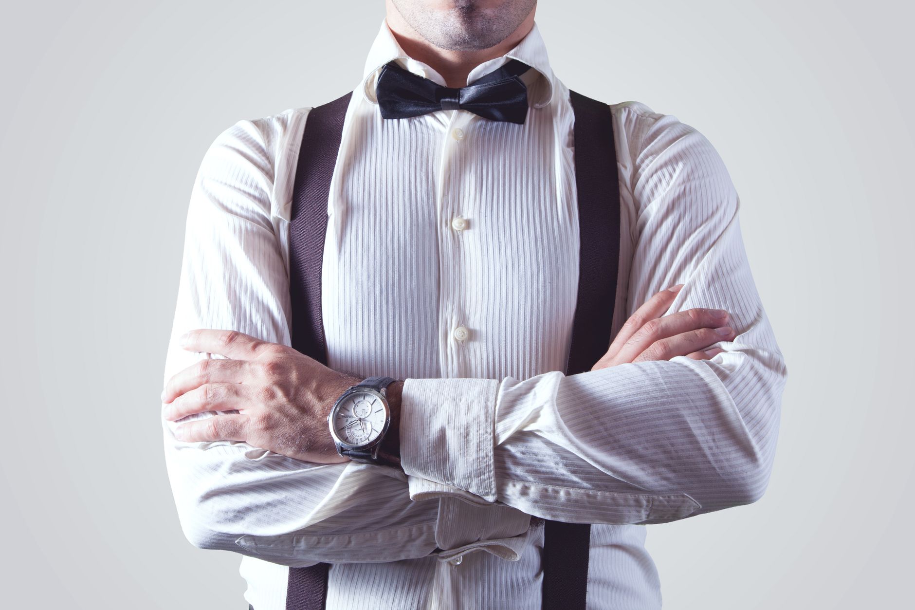 Man wearing charcoal chinos with black suspenders and a white dress shirt